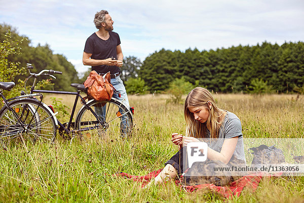 Couple with bicycles picnicing in rural field