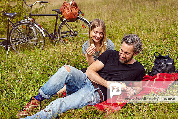 Ehepaar isst Äpfel beim Picknick auf dem Feld