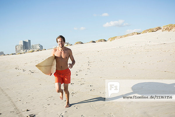 Young male surfer running on beach  Cape Town  Western Cape  South Africa
