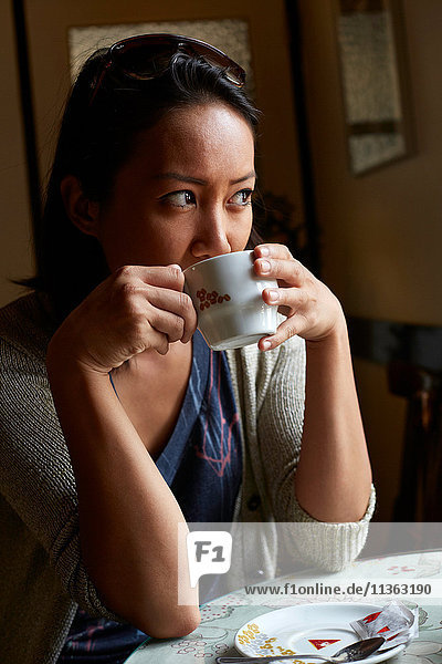 Young woman sitting inside cafe  drinking coffee