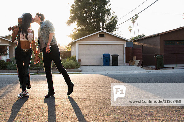 Junges Paar im Freien  küsst sich  junge Frau hält Gitarre