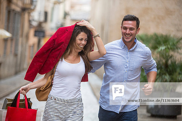 Couple laughing and running for shelter from rain