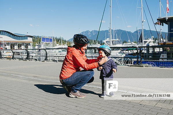 Mother putting protective helmet on son  British Columbia  Canada