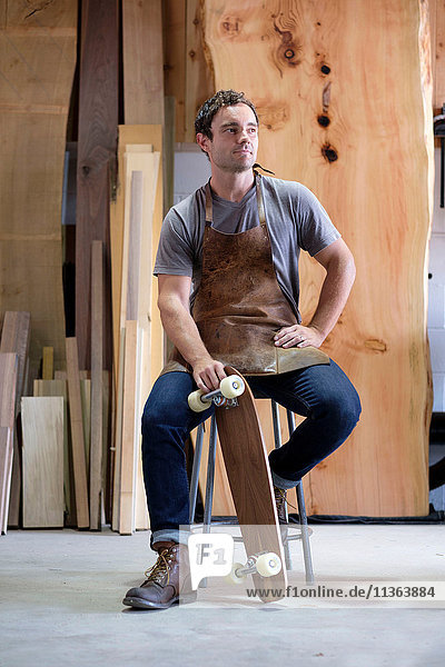 Carpenter at his workshop  holding skateboard