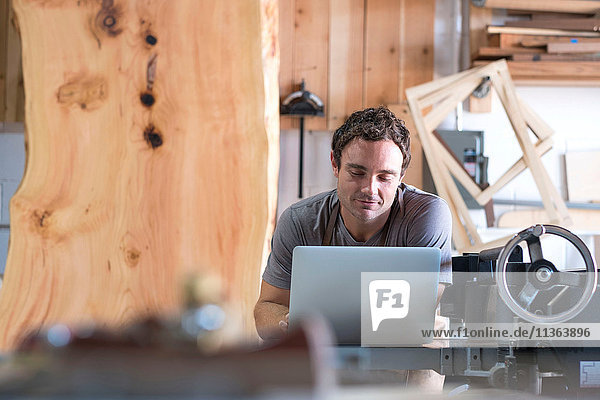 Carpenter at his workshop  using laptop