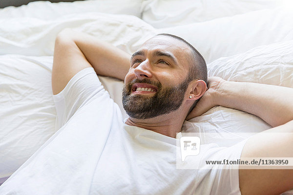 Happy mid adult man lying in bed