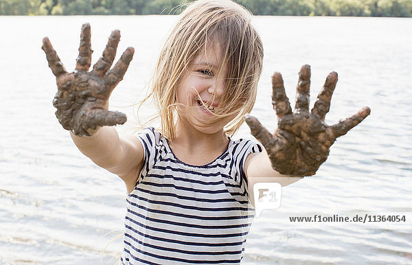 Porträt eines Mädchens mit schlammigen Händen im Fluss