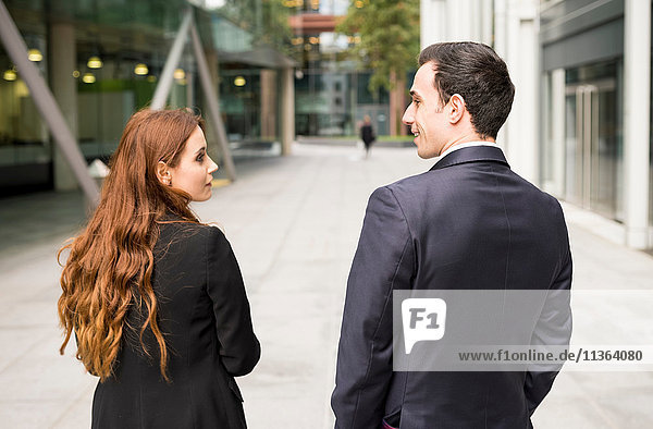Rear view of businesspeople in city face to face smiling