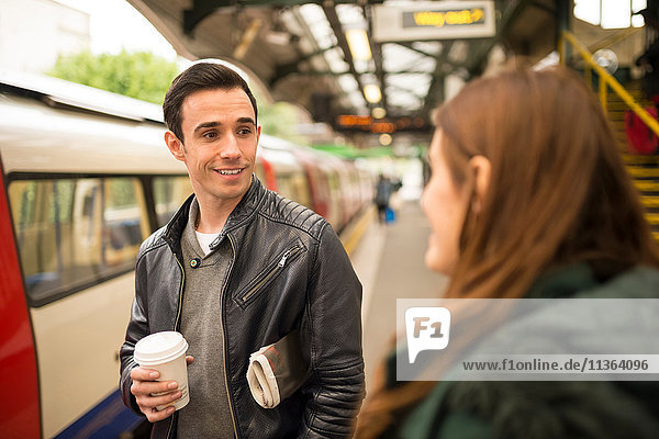Couple on railway platform face to face smiling