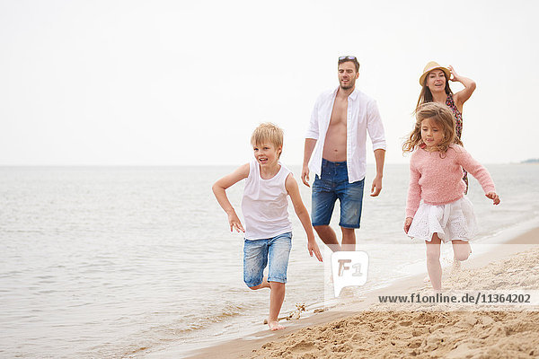 Family running along sandy beach