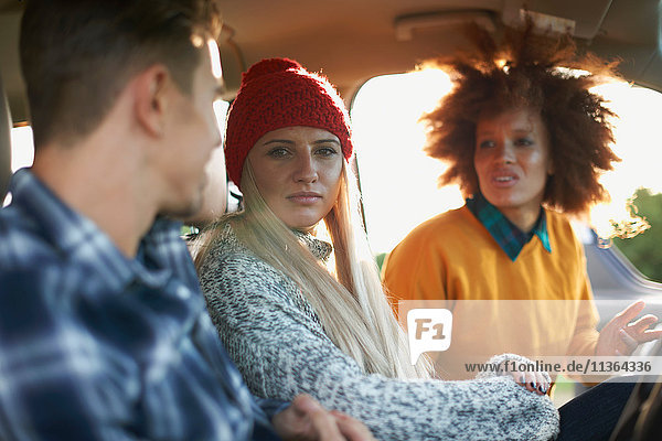 Drei junge erwachsene Freunde unterhalten sich im Auto