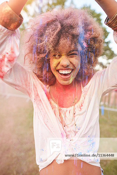 Porträt einer jungen Frau beim Festival  bedeckt mit bunter Pulverfarbe