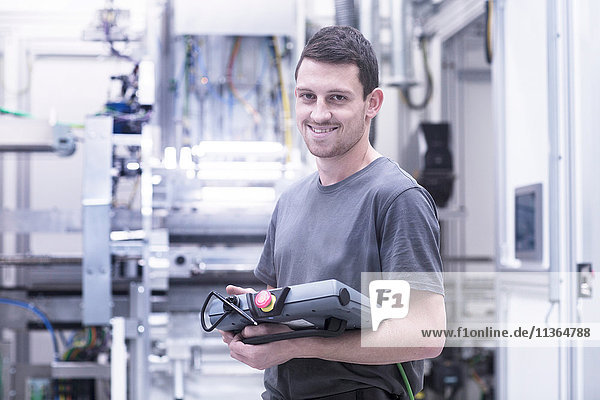 Porträt eines Ingenieurs  der elektronische Steuergeräte in einer Maschinenfabrik besitzt