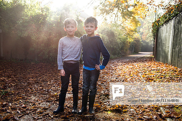 Porträt von Zwillingsjungen  im Freien  umgeben von Herbstlaub