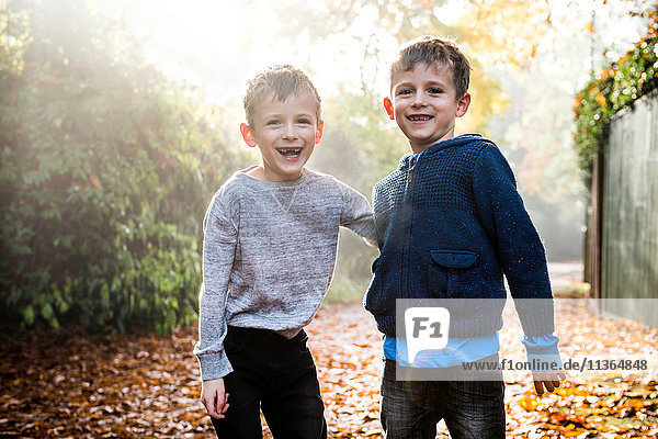 Porträt von Zwillingsjungen  im Freien  umgeben von Herbstlaub  lachend