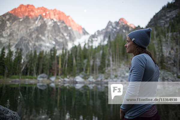 Young woman standing beside lake  looking at view  The Enchantments  Alpine Lakes Wilderness  Washington  USA