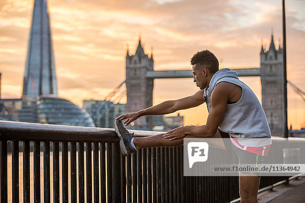 Mann streckt sich gegen Geländer  Tower Bridge und The Shard im Hintergrund  Wapping  London  UK