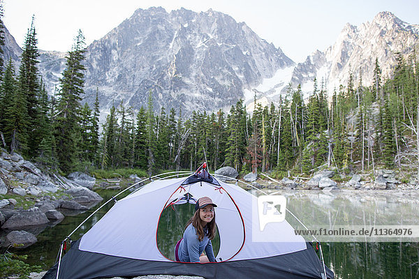 Young woman sitting in tent beside lake  The Enchantments  Alpine Lakes Wilderness  Washington  USA