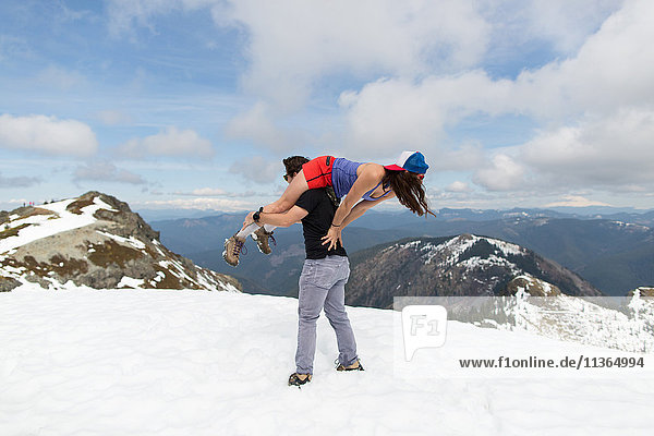 Man carrying woman over shoulder on mountain-top  Silver Star Mountain  Washington  USA