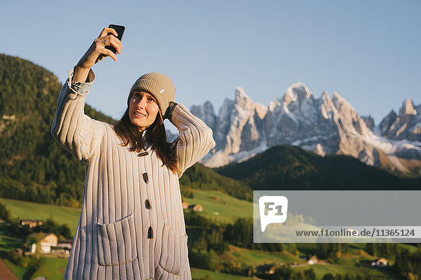 Woman taking selfie  Santa Maddalena  Dolomite Alps  Val di Funes (Funes Valley)  South Tyrol  Italy
