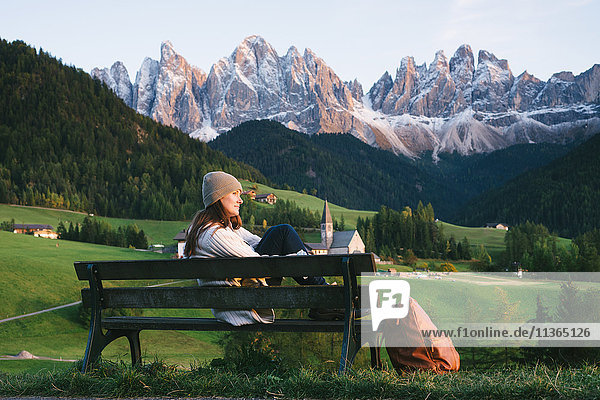 Woman relaxing on park bench  Santa Maddalena  Dolomite Alps  Val di Funes (Funes Valley)  South Tyrol  Italy