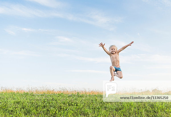 Junge im Feld springt in der Luft