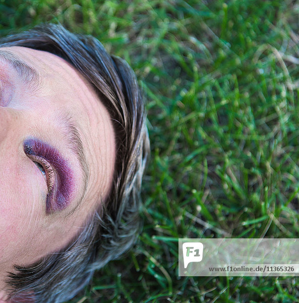 Schrägansicht eines Mannes mit schwarzem Auge  der auf Gras liegt