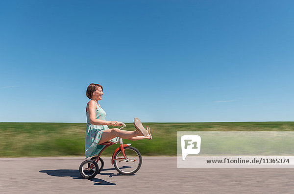Seitenansicht einer Frau auf einem Dreirad in einer ländlichen Gegend