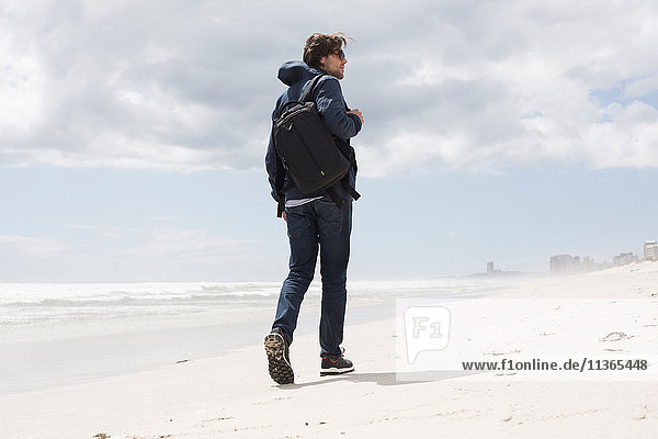 Rear view of young man strolling alone on beach  Western Cape  South Africa