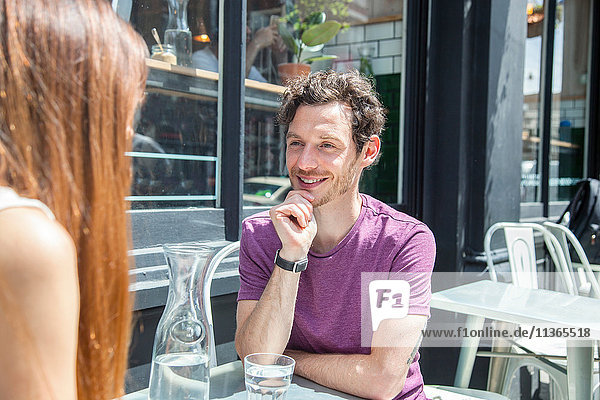 Mid adult couple chatting at city sidewalk cafe