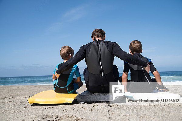 Rückansicht eines Mannes und zweier Söhne auf Bodyboards sitzend  Laguna Beach  Kalifornien  USA
