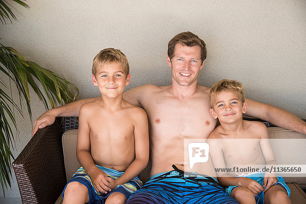 Portrait of man and two sons sitting on patio sofa  Laguna Beach  California  USA