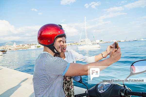 Young moped couple taking selfie at harbour  Split  Dalmatia  Croatia