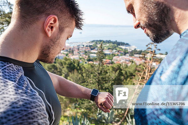 Zwei männliche Läufer überprüfen Smartwatch im Park  Split  Dalmatien  Kroatien