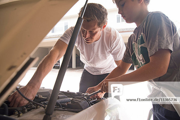 Father showing son car maintenance under car hood