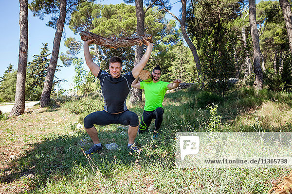 Two young men doing weightlifting training with logs in forest  Split  Dalmatia  Croatia