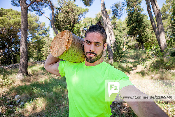 Young man doing weightlifting training with log in forest  Split  Dalmatia  Croatia