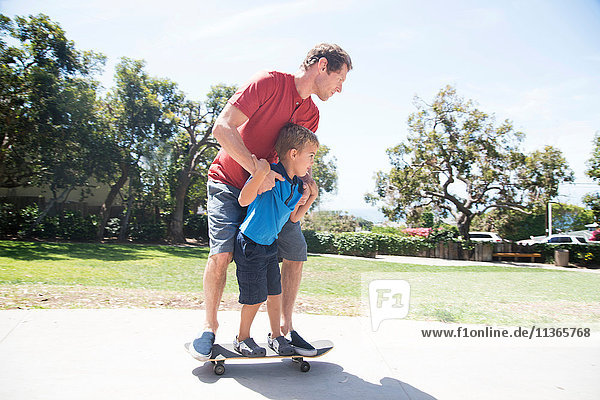 Vater und Sohn im Park beim Skateboardfahren