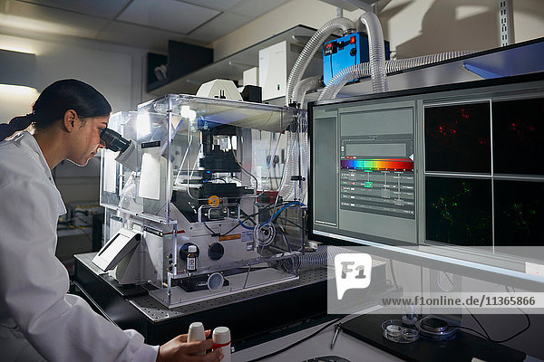 Wissenschaftlerin im Labor beim Blick durchs Mikroskop