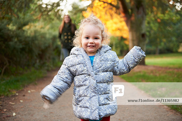 Glückliches weibliches Kleinkind läuft im Herbstpark