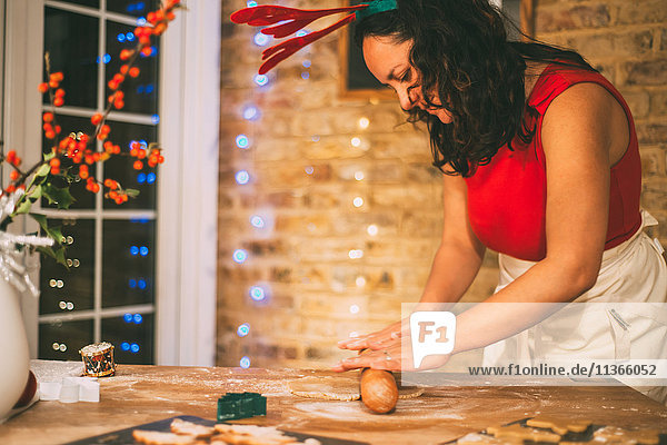 Reife Frau rollt Weihnachtsplätzchen an der Küchentheke