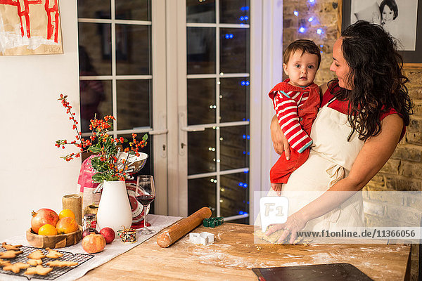 Reife Frau bereitet Weihnachtsplätzchen mit dem kleinen Sohn an der Küchentheke zu