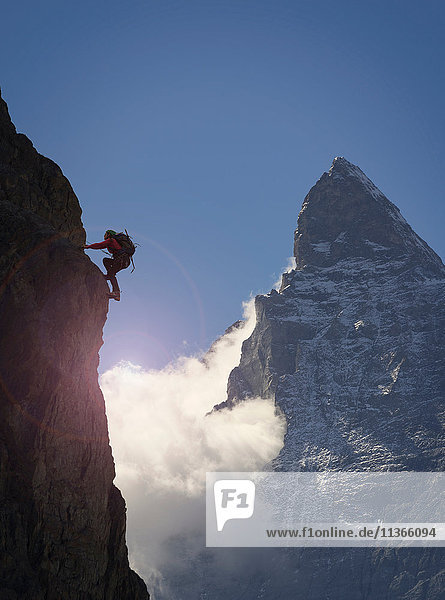 Silhouette einer Bergsteigerin beim Klettern an einer Felswand in der Nähe des Matterhorns Kanton Wallis Schweiz