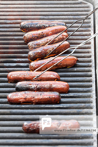 Row of sausages barbecuing on grill