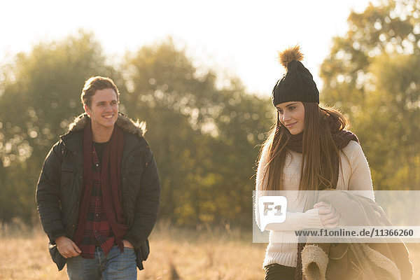 Junges Paar geht lächelnd durchs Feld
