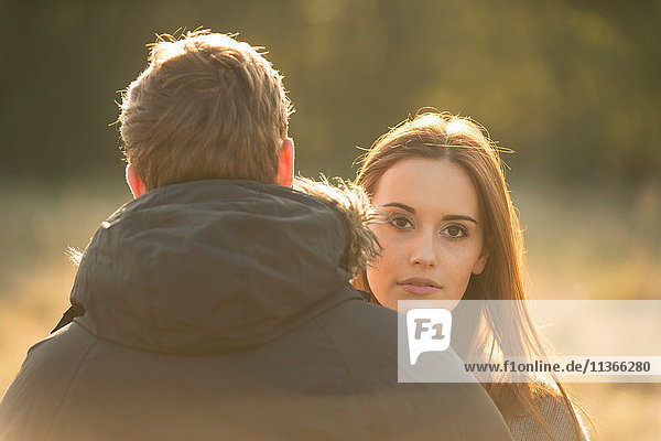 Junges Paar im Feld  junge Frau schaut dem Mann über die Schulter
