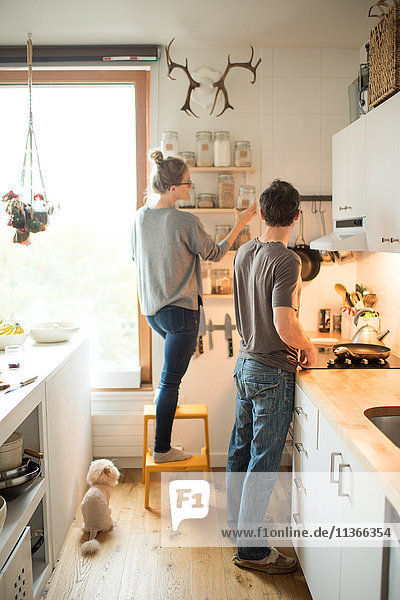 Frau und Freund wählen Ofenglas in der Küche