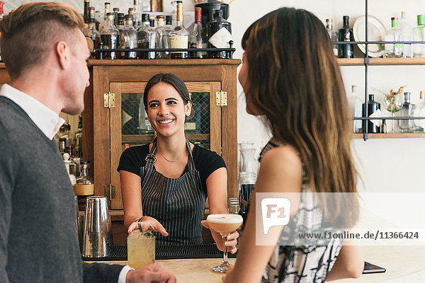 Waitress serving young couple in cocktail bar