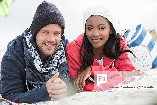 Porträt eines jungen Paares auf einer Picknickdecke am Strand liegend Western Cape Südafrika