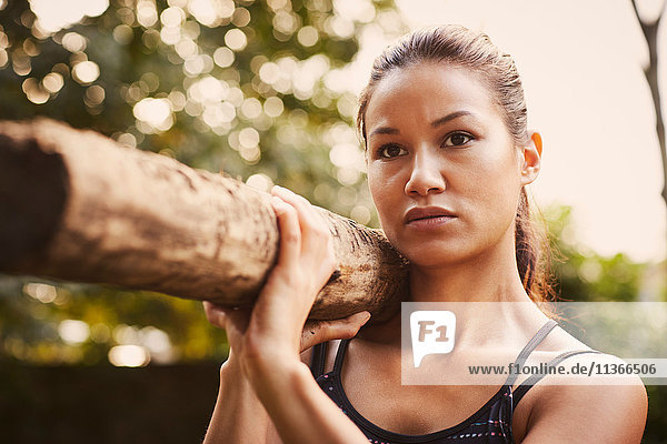 Porträt der Frau beim Training  Baumstamm auf Schulter heben im Park